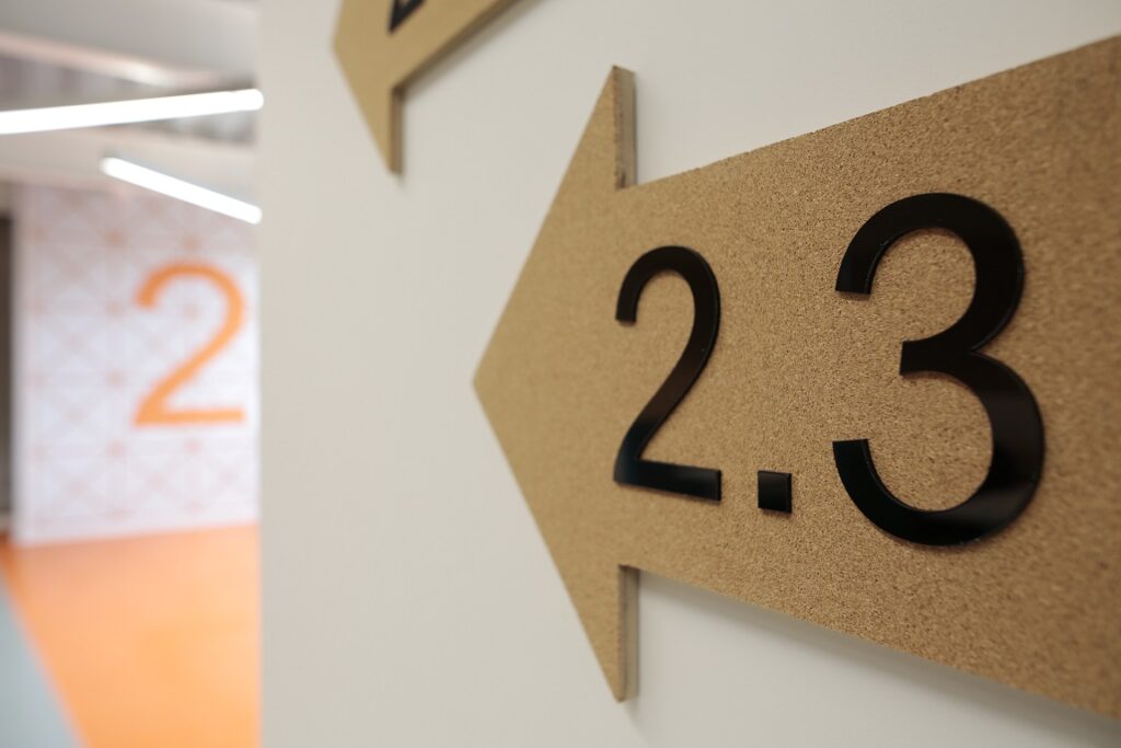 Roxburgh Place MDF Arrow directory with acrylic text applied to the face and Painted MDF Numeral Floor 2 Indicator.