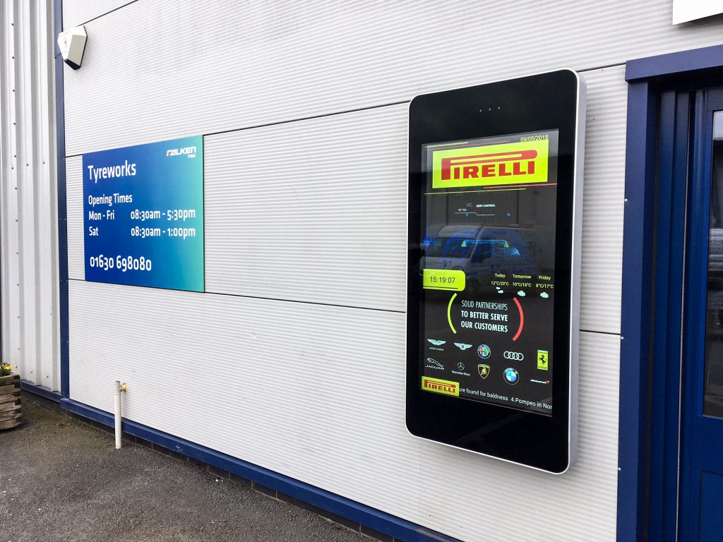 Digital display fitted to the cladding outside of a garage showing an Ad for Pirelli Tyres