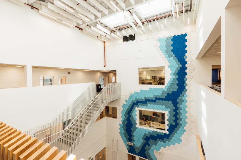 Currie Community High blue geometric pattern in digitally printed vinyl applied to an internal painted wall from the ground floor up to the second. Signage in Passivhaus Schools