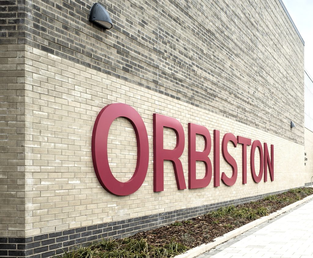 Orbiston Community Hub large scale powder coated red text fitted to external brickwork