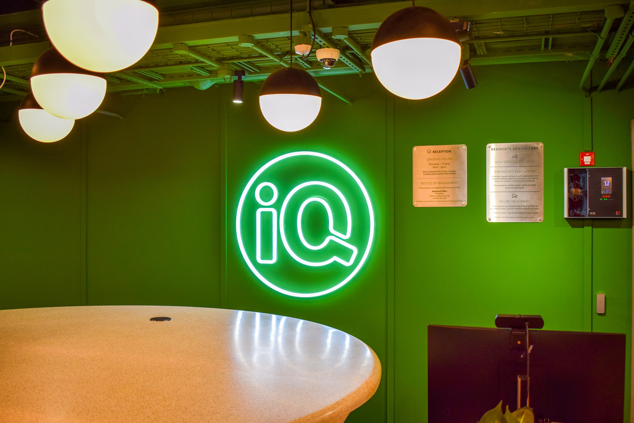 iQSA Cullen House Signage bespoke neon sign of the iQ logo on a green wall in the reception area of Cullen House