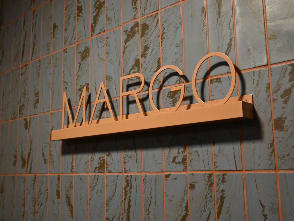 Powder coated aluminium text reading MARGO fitted to an internal tile wall