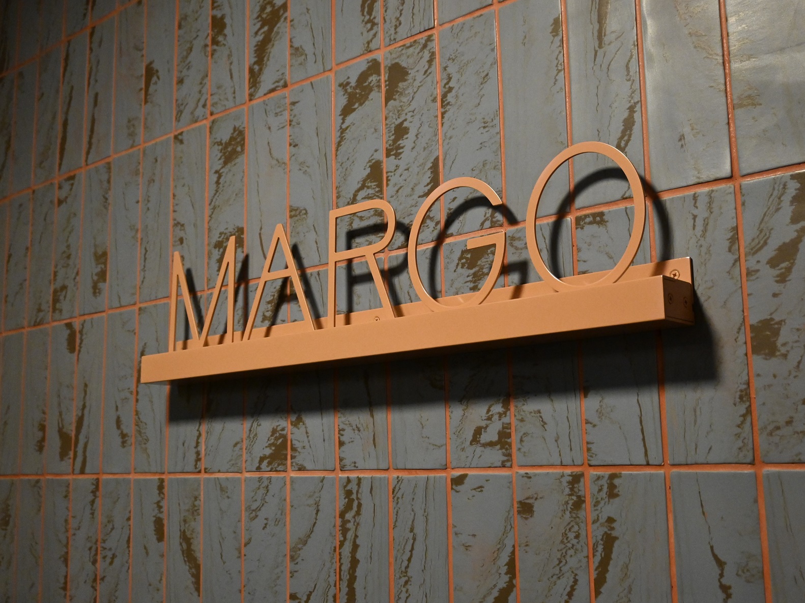 Powder coated aluminium text reading MARGO fitted to an internal tile wall